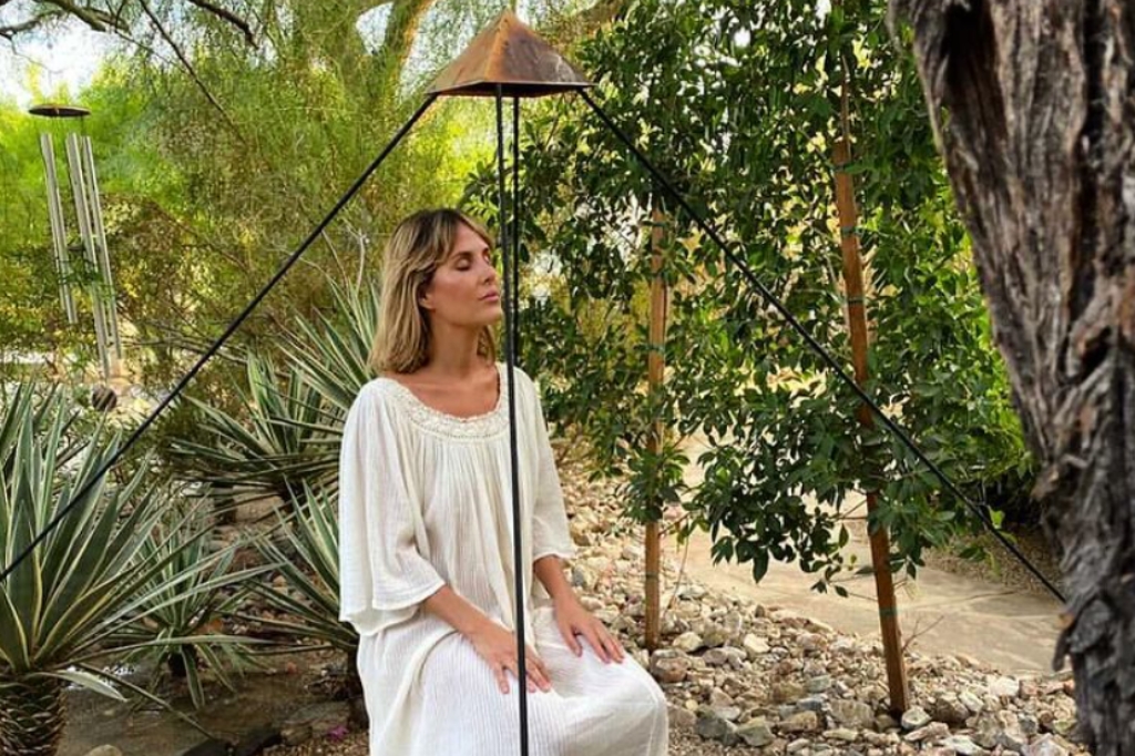 At the Holistic Detox Center, a woman in a white dress sits gracefully on a chair, embodying peace and wellness.