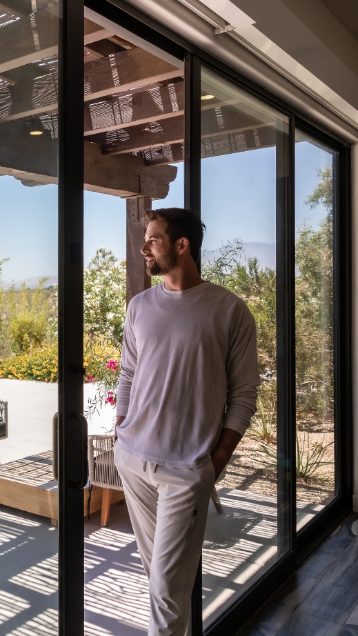 A man stands before a sliding glass door at the Holistic Detox Center, embodying tranquility and holistic health.