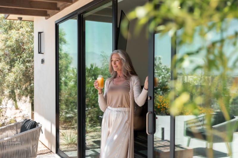 A woman enjoys a glass of wine outside her home, illustrating everyday habits for improving gut health naturally.