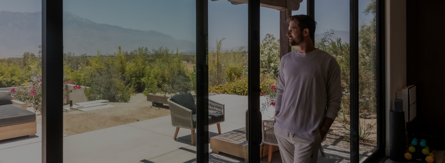 A man stands in front of a sliding glass door at the Colon Cleansing SPA, looking out into the surroundings.