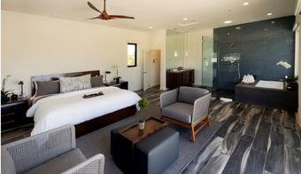 A spacious bedroom featuring a large bed and a bathtub, showcasing the Colonic Palm Springs for a 2-night stay.