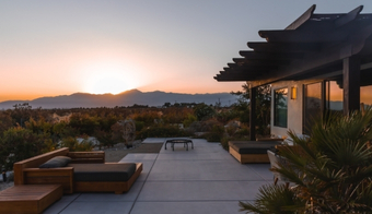 A serene patio overlooking a sunset with mountains, promoting a 7-night stay at a colonic retreat.