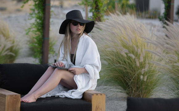 A woman wearing a robe and hat relaxes in a chair at the Holistic Detox Center, embodying tranquility and wellness.