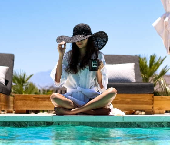 A woman in a hat enjoys the poolside atmosphere at the Juice Fast Detox Retreat.