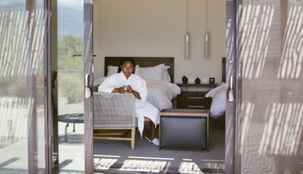 A woman in a robe sits on a bed in a room, promoting a two-night stay for Liquid Nutrition for Adults.