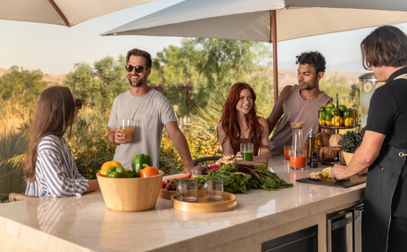 A group of people socializing around a bar, enjoying food and drinks, promoting Liquid Nutrition for Adults.