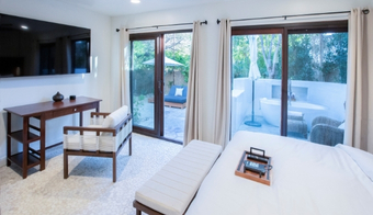 A stylish bedroom with sliding glass doors and a television, highlighting a 5-night stay at the Wellness Center Palm Springs.