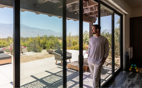 A man stands near a sliding glass door, showcasing the Wellness Center in Palm Springs.