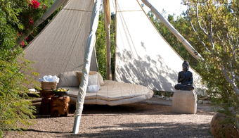 Cozy teepee tent with a bed and a Buddha statue, representing a tranquil two-night stay at a wellness destination spa.