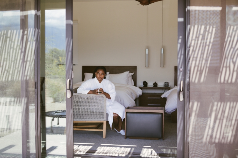 A woman in a serene room with a bed and window, contemplating the benefits of fasting and spirituality.