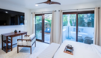 A cozy bedroom featuring sliding glass doors and a television, part of a 2-night holistic detox program stay.