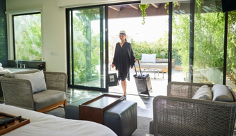 A woman walks in a bedroom with a large glass door, reflecting a peaceful environment for a holistic detox program.