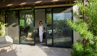 A woman stands by a sliding glass door, promoting a Liquid Cleanse Detox two-night stay experience.