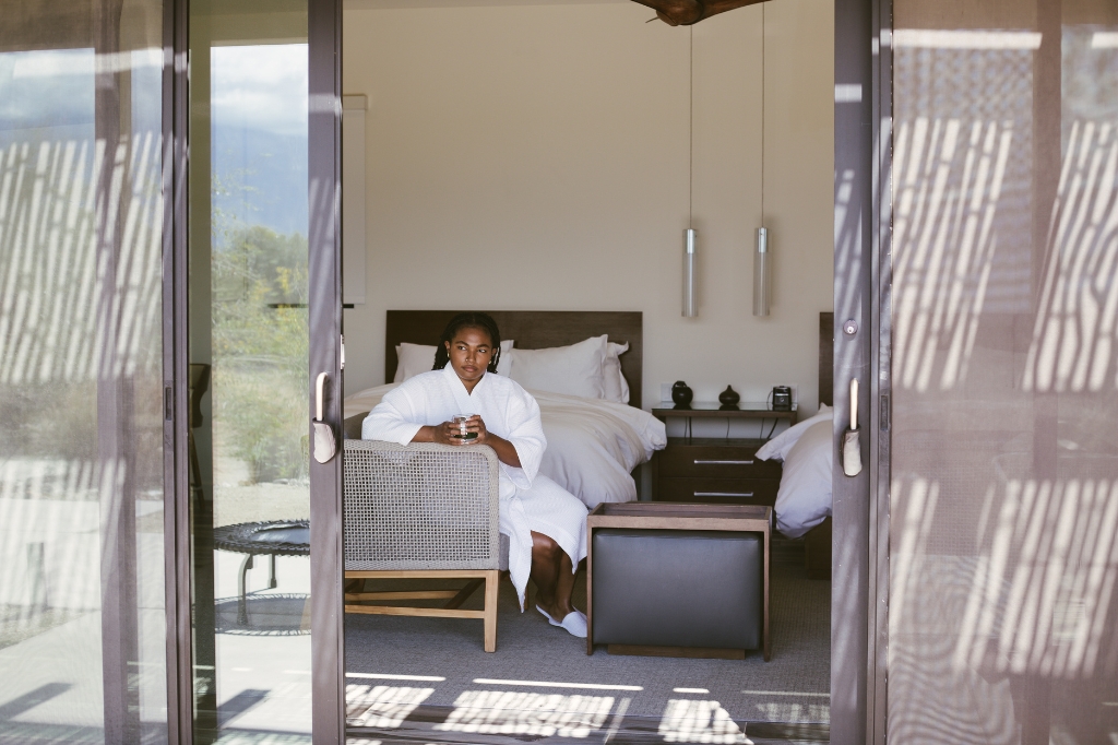 A woman sitting in a room, focused on a Liquid Cleanse Detox program, surrounded by wellness materials.