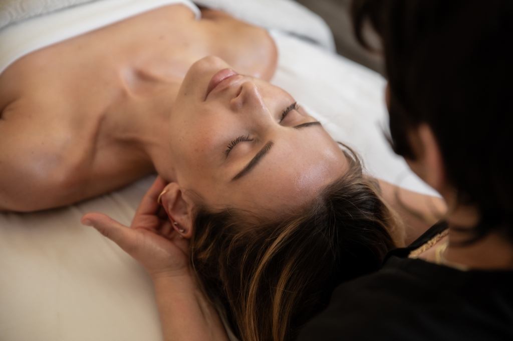 A woman experiencing a facial massage at Rejuvenation Spa Retreat, with soothing ambiance and spa elements enhancing her experience.