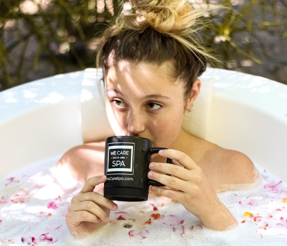 A woman sits in a bathtub with a coffee mug, embodying relaxation at the Rejuvenation Spa Retreat.