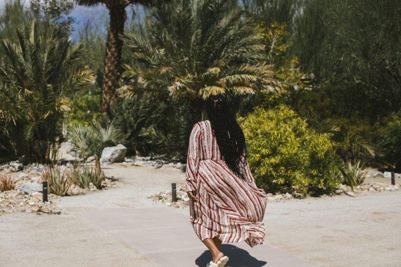 A woman in a striped dress walks through a vast desert, symbolizing the journey of autophagy and fasting for longevity.