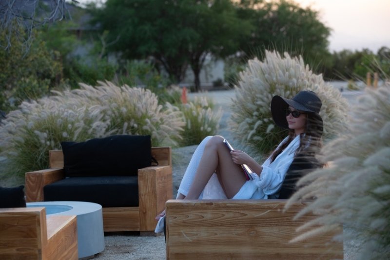 In the desert, a woman rests on a wooden bench, contemplating the benefits of fasting and autophagy for mental clarity.