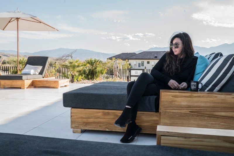 A woman relaxes on a couch, gazing at a stunning mountain view, reflecting on autophagy and extended fasting.