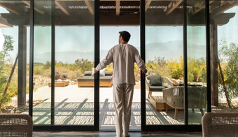 A man stands before sliding glass doors, looking out at the desert landscape during his 7-night stay at a Colon Hydrotherapy Spa.
