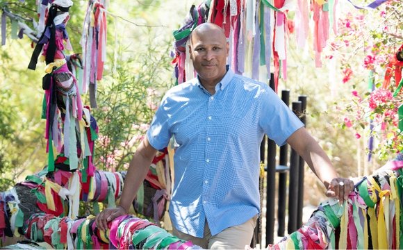 A man stands in front of a vibrant ribbon arch at the Colon Hydrotherapy Spa, showcasing a festive atmosphere.