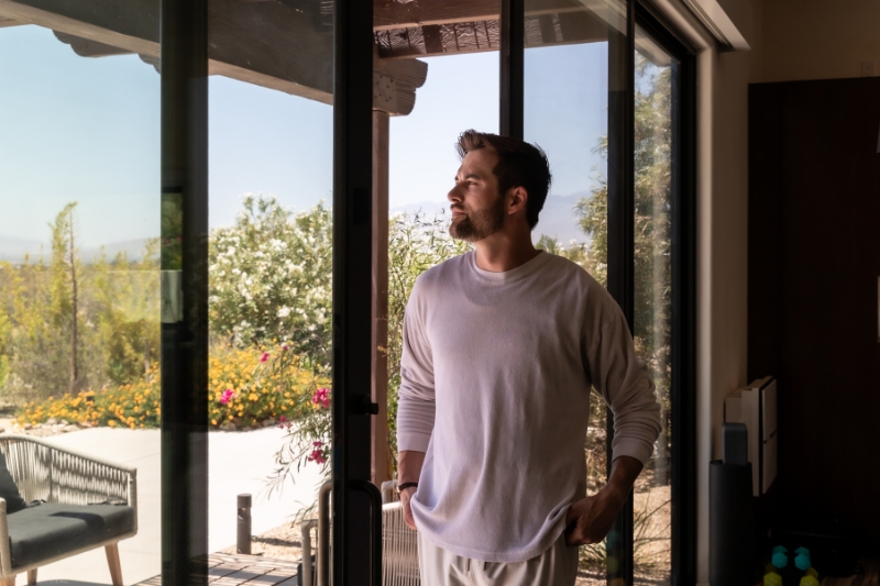 A man in front of a sliding glass door, considering the implications of detox for health and weight loss.
