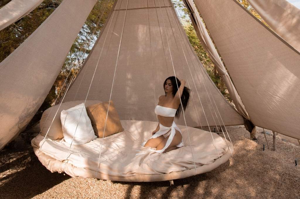 A woman sits comfortably in a swing bed at a Detox Spa Retreat, with the vast desert scenery surrounding her.