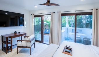 A serene bedroom with sliding glass doors and a television, set up for a two-night stay on a Liquid Diet Detox program.
