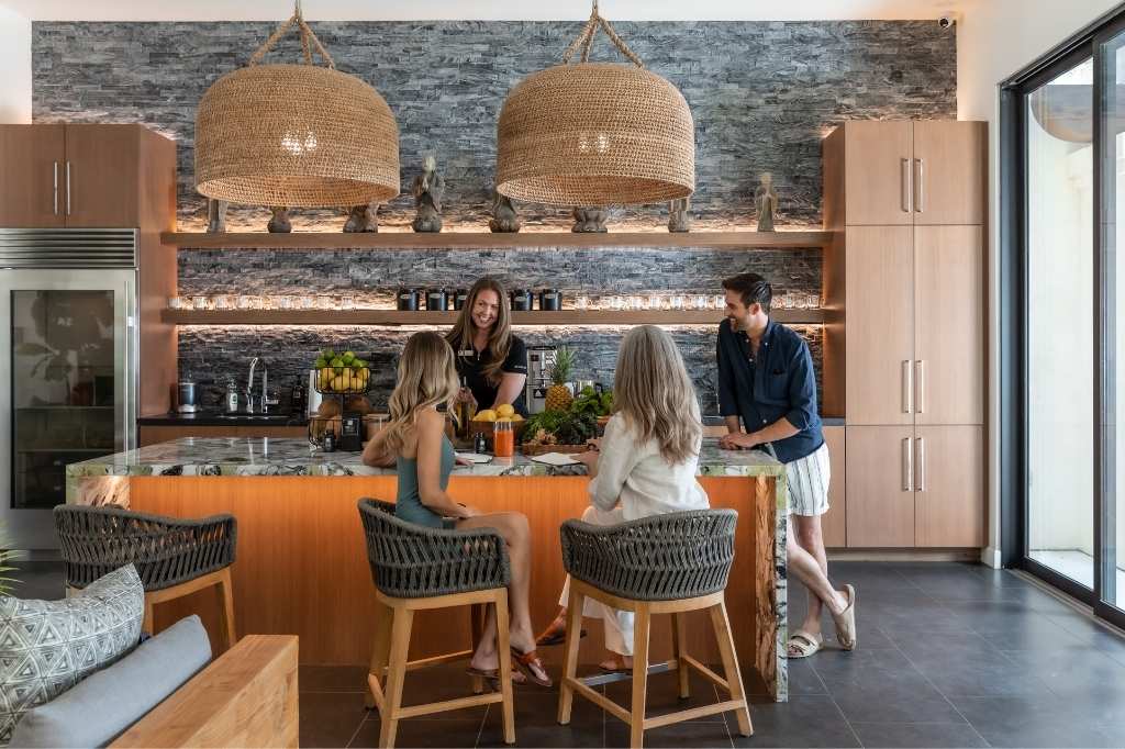 Several individuals seated at a kitchen island, engaged in conversation about a Liquid Diet Detox.