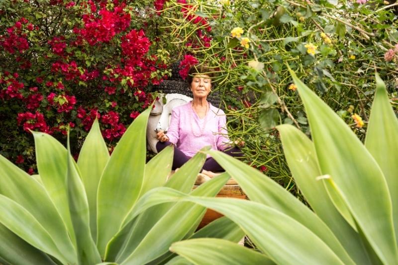 Woman meditating in garden, promoting mental clarity at wellness detox retreat