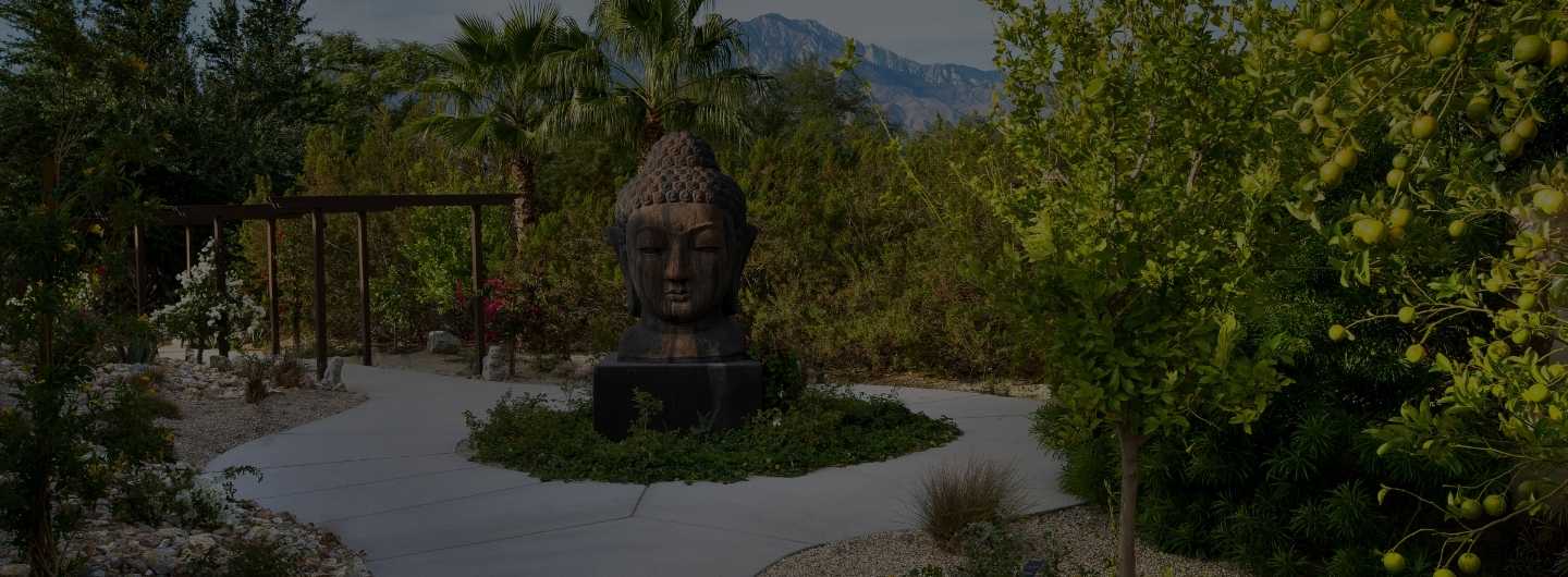 Palm Springs wellness resort garden with Buddha statue, desert landscape, and mountain views