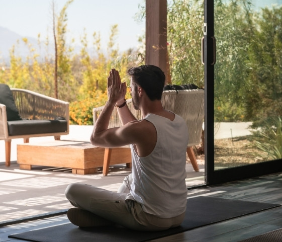Man practicing meditation indoors at a California wellness retreat with garden views