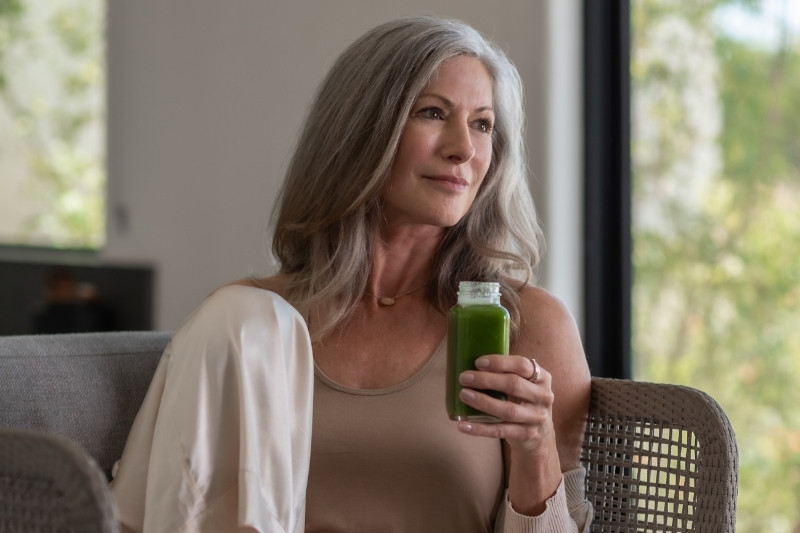 A wellness guest relaxes indoors while drinking a nutrient-rich green juice to support natural detoxification.