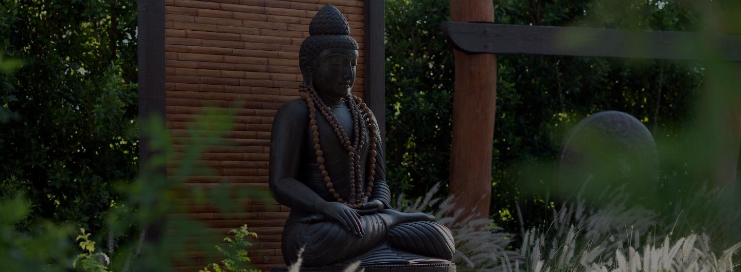 Serene Buddha statue in a lush California luxury wellness retreat garden