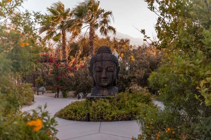 Tranquil garden path with Buddha statue creating a peaceful setting for renewal.