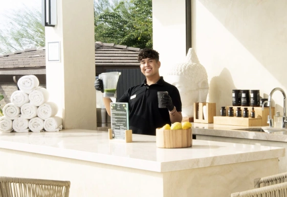 We Care Spa team member serving a fresh wellness drink at the outdoor juice bar.