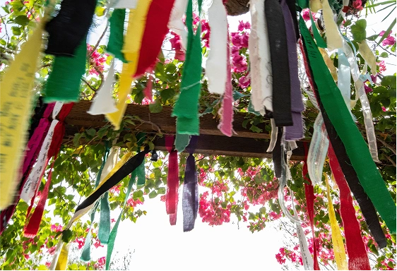 Colorful prayer ribbons hanging among flowers at We Care Spa detox spa retreat.