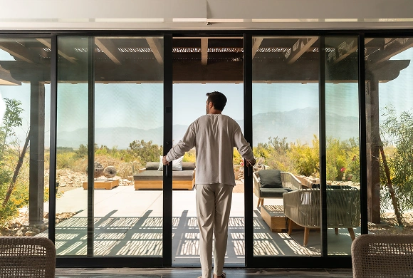 Guest opening glass doors to a peaceful desert retreat surrounded by nature, supporting digestive wellness.