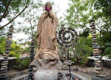 Stone Virgin Mary statue and stacked stone sculptures in We Care Spa’s wellness garden.