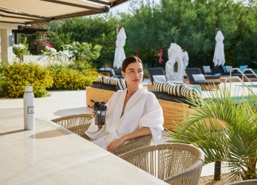 Woman enjoying a wellness drink by the pool at We Care Spa’s holistic retreat.