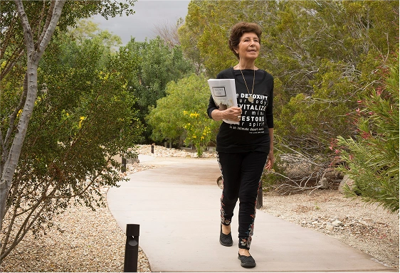 Susana walking through the garden at We Care Spa while sharing her wellness teachings.