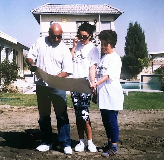 Historic We Care Spa photo showing three people reviewing plans during the spa’s early development.